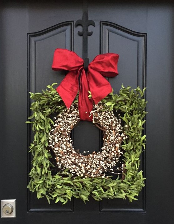 a pretty frame Christmas wreath covered with greenery and with a blooming wreath inside plus a large red bow on top