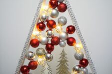 a shiny and glam tabletop Christmas tree with silver, glitter and red ornaments, some glitter trees and deer and lights inside