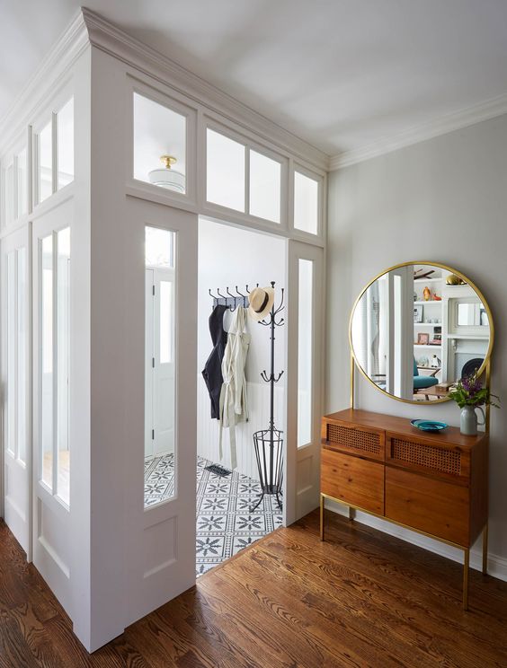 a small and lovely entryway done with glass walls and transom windows to fill it with light and the space around it, too