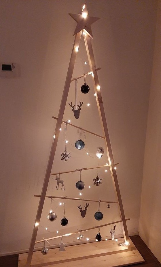 a stained frame Christmas tree with lights, irregularly placed railings, white, black and silver ornaments of various shapes