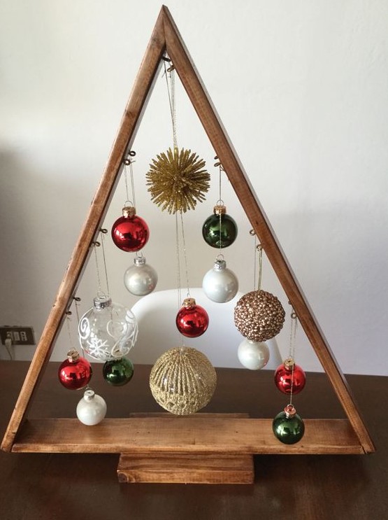 a stained tabletop Christmas tree with white, red, gold and clear ornaments hanging down is a bright and cool decoration