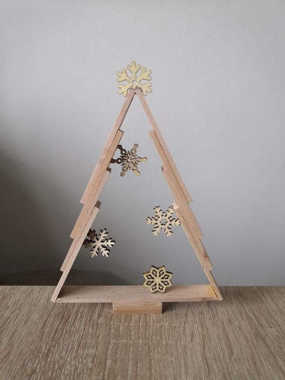 a tabletop frame Christmas tree decorated with some wooden snowflakes inside is a stylish idea for rustic decor