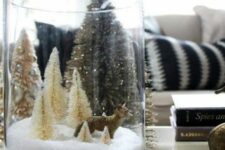 a tall glass Christmas terrarium with faux snow, neutral bottle brush trees and a fox is a cool idea that is easy to recreate