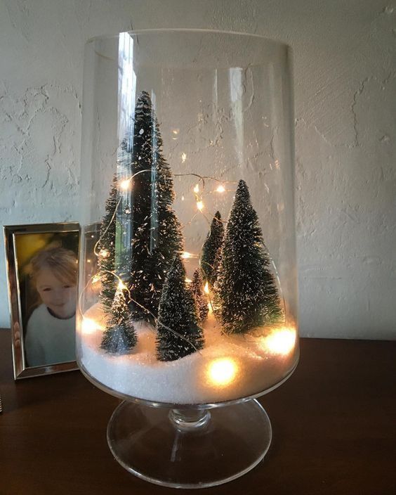 a tall glass terrarium with faux snow, some bottle brush trees and lights is easy to make yourself and looks cool