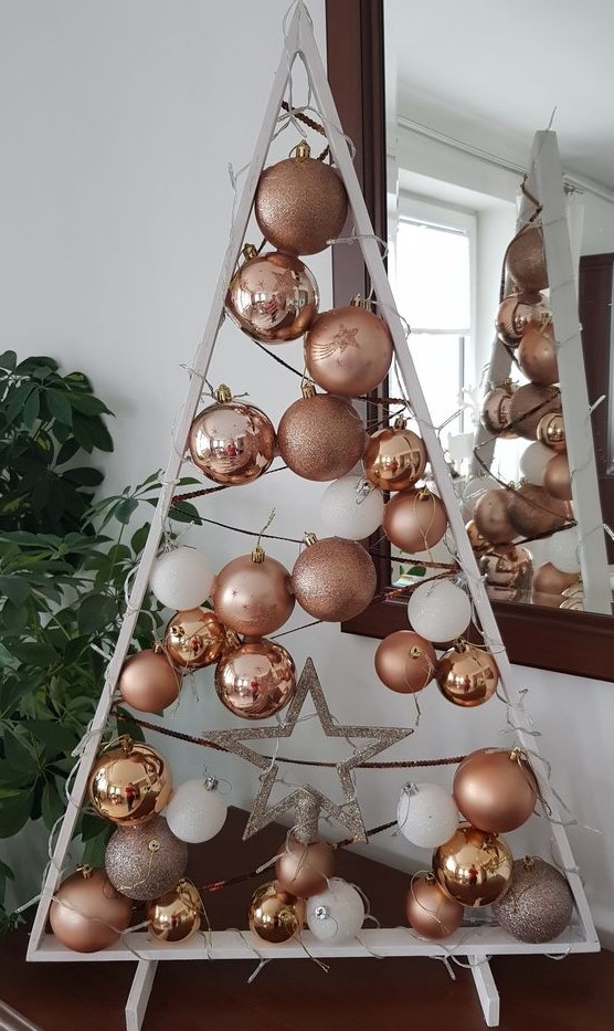 a white frame Christmas tree with threads, copper, rose gold and white ornaments hanging plus a silver star is cool
