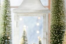 a whitewashed lantern with a snowy scene inside – a little house and bottle brush trees for vintage Christmas decor