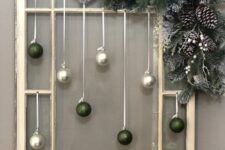 a window frame Christmas decoration with pearl and green glitter ornaments, evergreens, pinecones and white berries