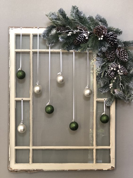 a window frame Christmas decoration with pearl and green glitter ornaments, evergreens, pinecones and white berries