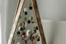 a woodland frame Christmas tree decorated with white, black, grene and gold ornaments, branches, a squirrel and an owl is fun