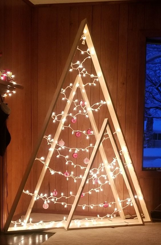 an arrangement of plywood Christmas trees with lights and red and white ornaments is a super stylish modern solution