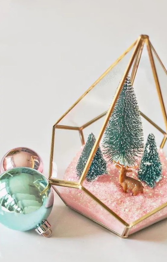 an elegant Christmas terrarium with pink faux snow, green bottle brush trees and a little deer figurine is chic and cute
