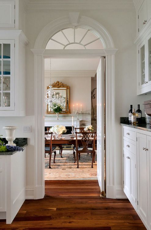 an elegant vintage space in white with white furniture, a small arched transom window and a matching door