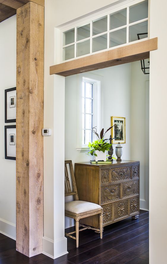 an opening with a transom window highlighted with a wooden beam plus some wooden pillars next to it to cozy up the space
