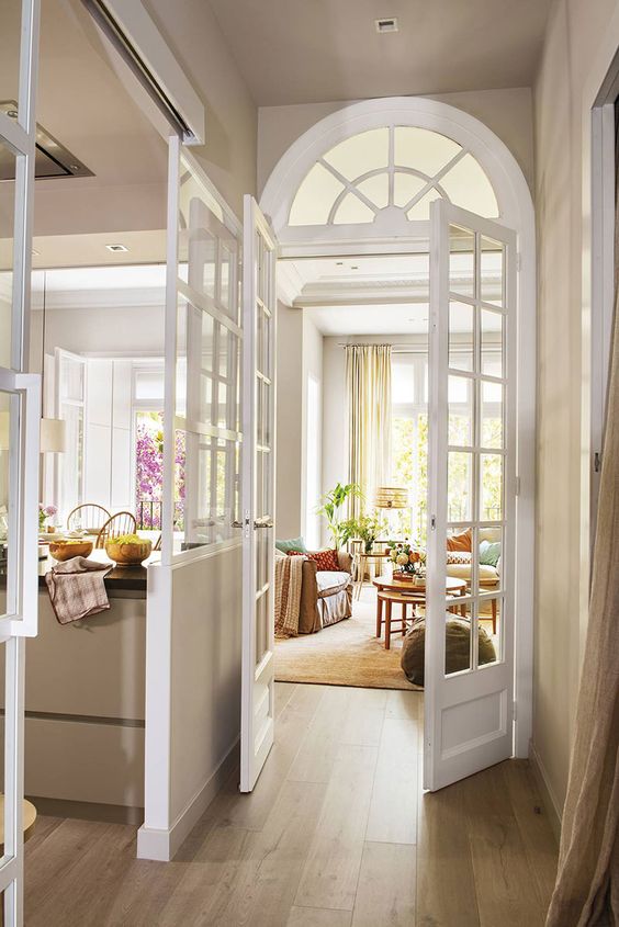beautiful French doors paired with an arched transom window and French sliding doors keep up the style of the space