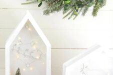 beautiful house-shaped white terrariums with bottle brush trees and deer silhouettes plus lights and stars
