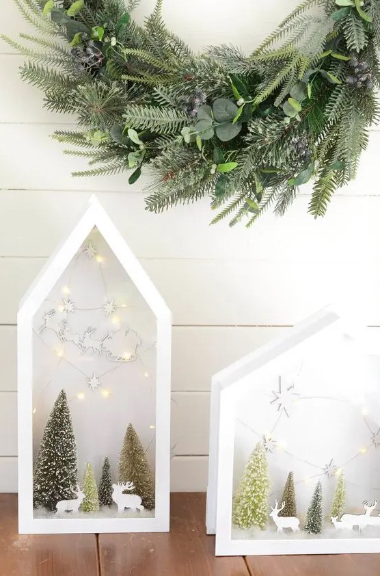 beautiful house-shaped white terrariums with bottle brush trees and deer silhouettes plus lights and stars