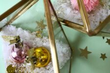 glam Christmas terrariums made of gilded triangles with faux snow, glitter and bright ornaments or a bottle brush tree