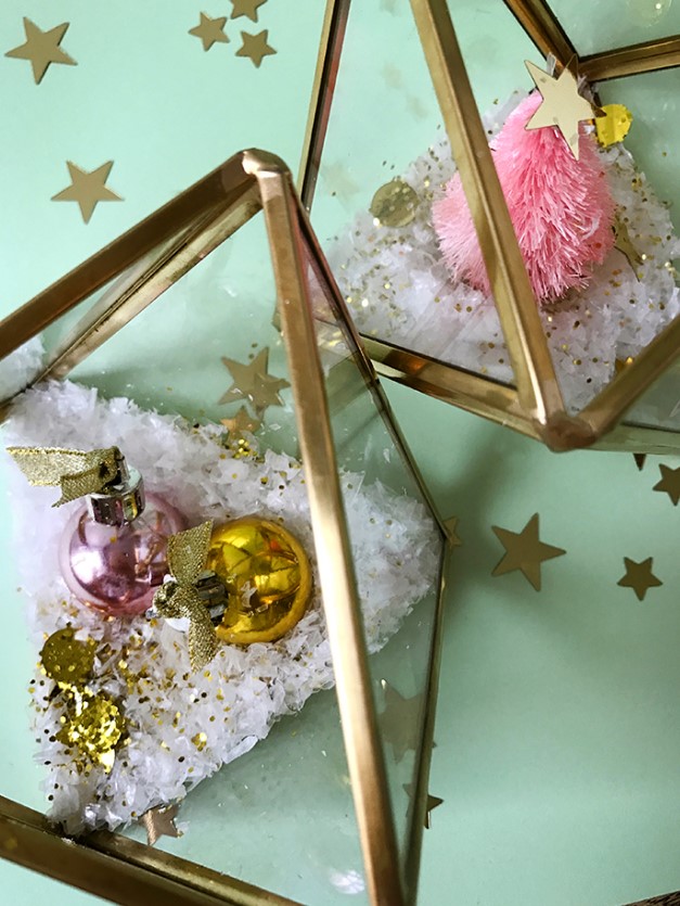 glam Christmas terrariums made of gilded triangles with faux snow, glitter and bright ornaments or a bottle brush tree