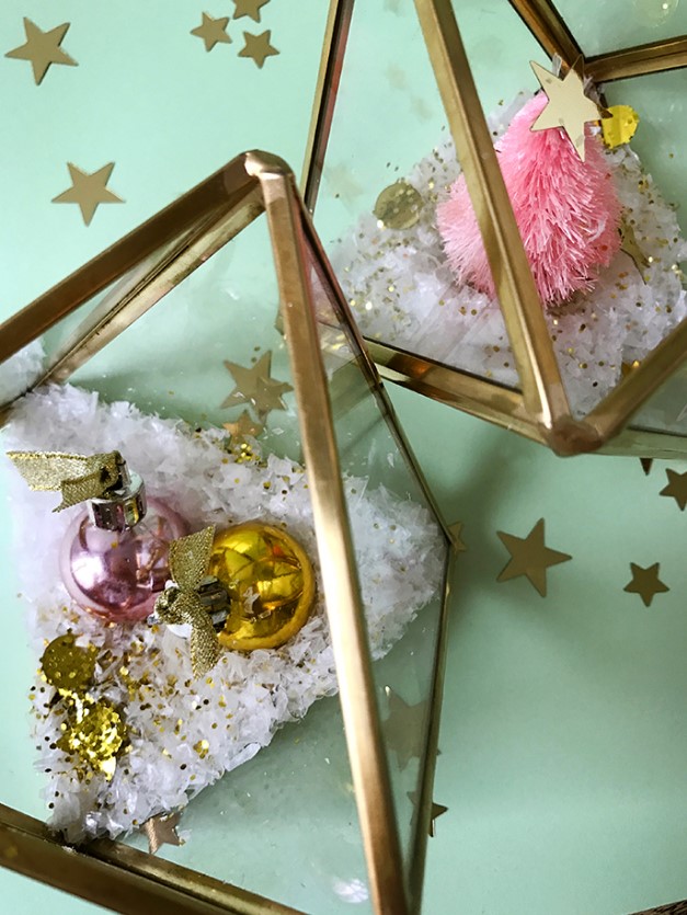 glam Christmas terrariums made of gilded triangles with faux snow, glitter and bright ornaments or a bottle brush tree