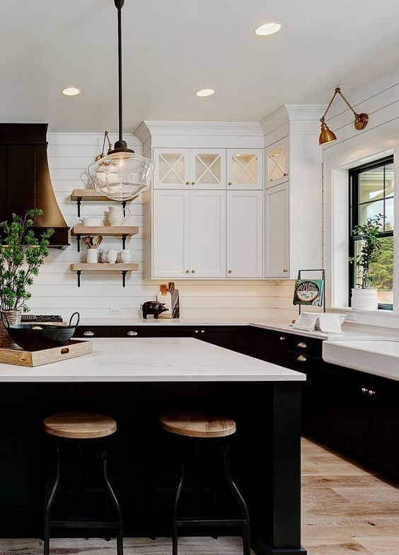 a black and white farmhouse kitchen with slatted walls, black and white shaker cabinets and a black black kitchen island