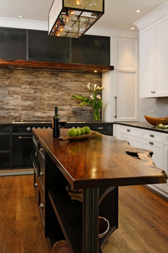 a black and white farmhouse kitchen with shaker cabinets, a black kitchen island with a living edge and a wood tile backsplash