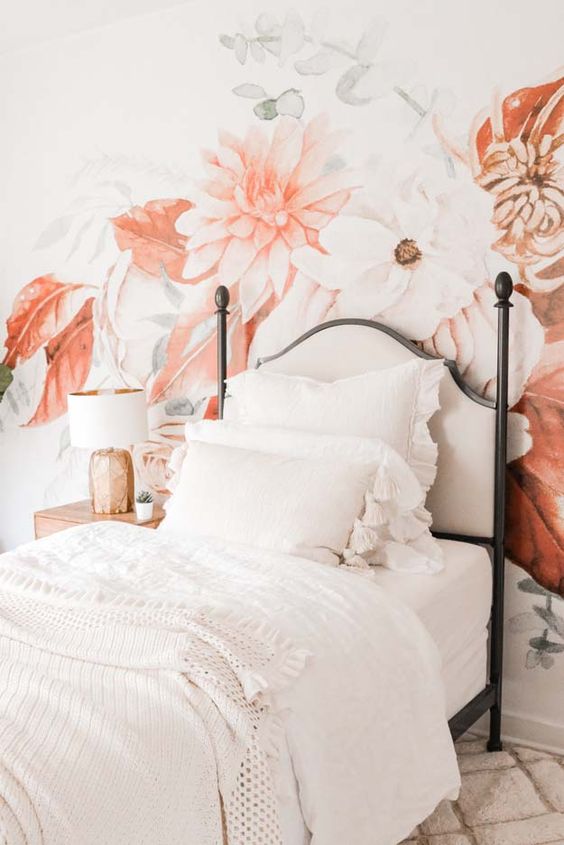 a chic teen bedroom with a floral accent wall, a vintage bed with white shabby chic bedding and a nightstand with a table lamp