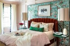 05 a colorful vintage bedroom with paneling, a bright floral wall, a burgundy bed, colorful bedding and a crystal chandelier