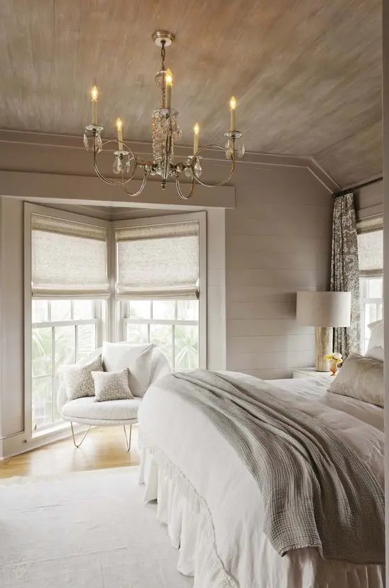 a neutral chalet bedroom with a vintage crystal chandelier, neutral furniture and bedding and pretty lamps