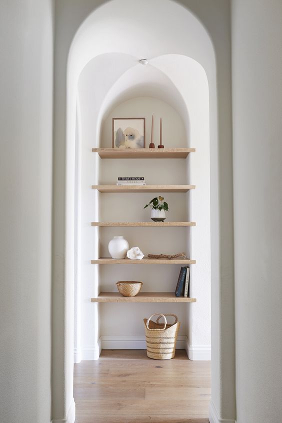 a large arched niche with wooden shelves for displaying stuff is a cool solution for an awkward nook