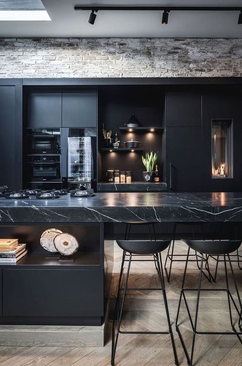 a contemporary black kitchen with a large kitchen island with a marble countertop, built-in lights and metal stools