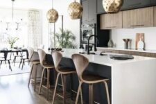09 a contemporary kitchen with stained and black cabinets, a black kitchen island, white countertops and a backsplash, gold scale pendant lamps