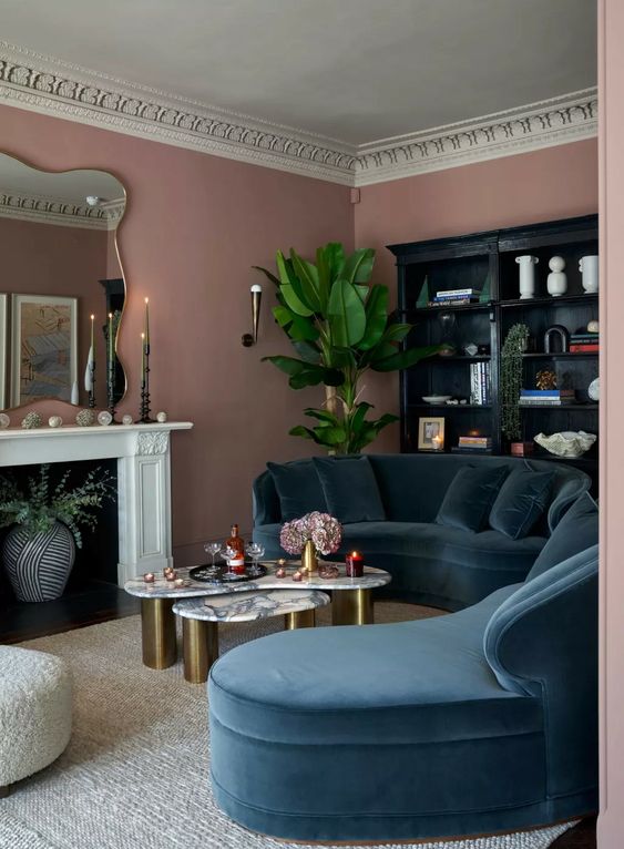 a beautiful living room with mauve walls, a fireplace, a navu curved sofa, a black storage unit and a potted plant