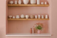 13 a pink dining room with an arched niche with stained shelves used to display vases and a built-in cabinet with drawers