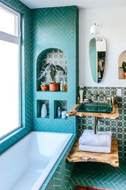 a turquoise bathroom with an arched and a couple of usual niches next to the tub clad with herringbone tiles