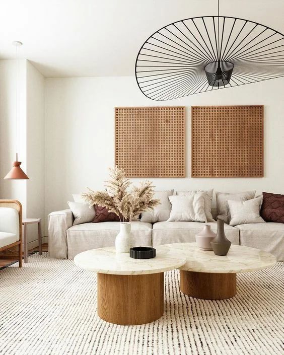 a beautiful warm-colored living room with a low sofa and neutral pillows, a chair, a couple of side tables and woven artwork