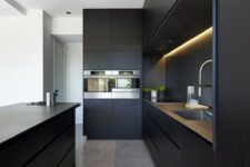 17 a minimalist black kitchen with sleek cabinets, built-in lights, a large kitchen island and built-in appliances