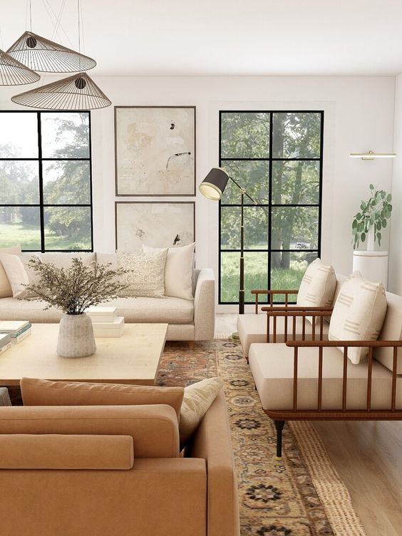 a warm-colored neutral living room with a creamy sofa and chairs, a rust-colored sofa, a printed rug and artworks
