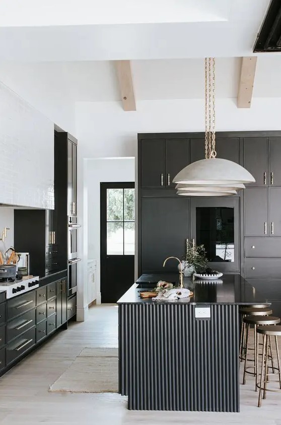 a modern black and white kitchen with black cabinetry, a white tile hood and a black fluted kitchen island with glossy countertops