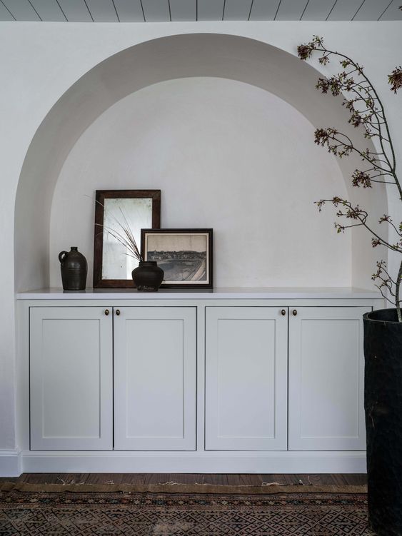 an arched niche with artwork and vases, built-in cabinets for storage will add interest to any space