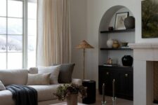 20 an arched niche with black shelves, vases and artwork, a black built-in cabinet for storage is a great idea