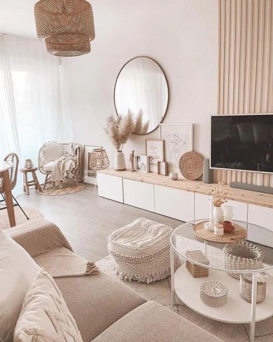 a warm neutral boho living room with a sofa and a wovne pouf, a tiered coffee table, a wood slat wall and a TV unit