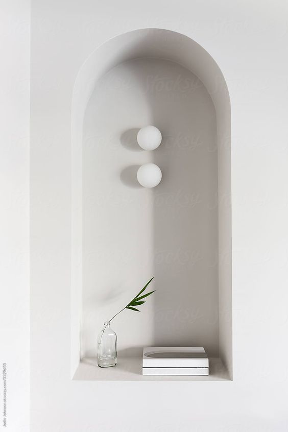 an arched niche with minimalist decor   two lamps, a vase and a couple of books will add interest to a minimalist interior