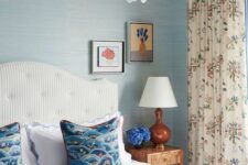23 a breezy bedroom with blue wallpaper walls, a white striped bed with blue bedding, floral curtains and a catchy scallop chandelier