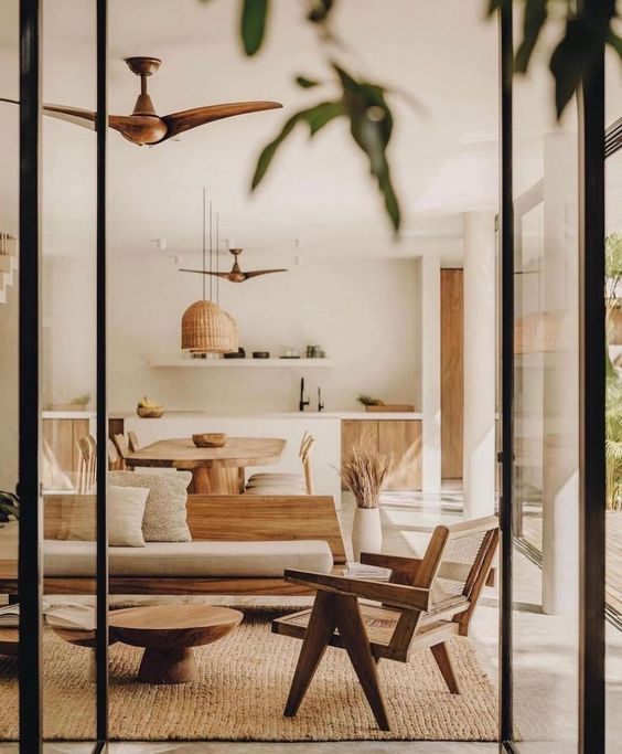 a neutral Mediterranean minimal living room with a wood sofa and soft upholstery, a woven chair, a coffee table