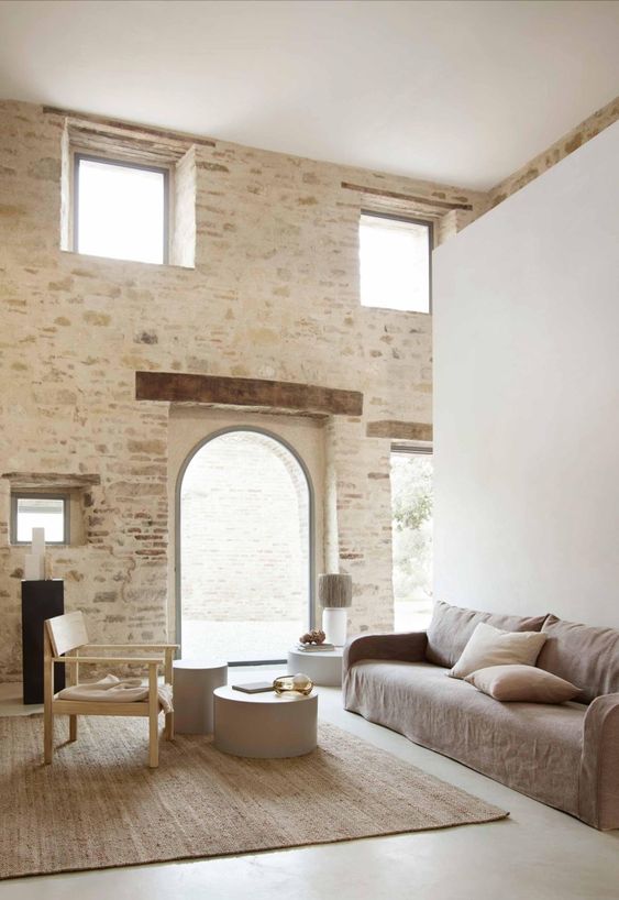 a welcoming minimalist Mediterranean living room with a grey sofa and neutral pillows, round side tables and a neutral chair