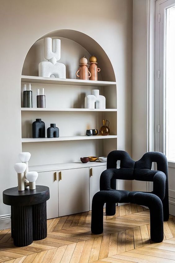 an arched niche with shelves that are used to display beautiful decor and candleholders and built in cabinets