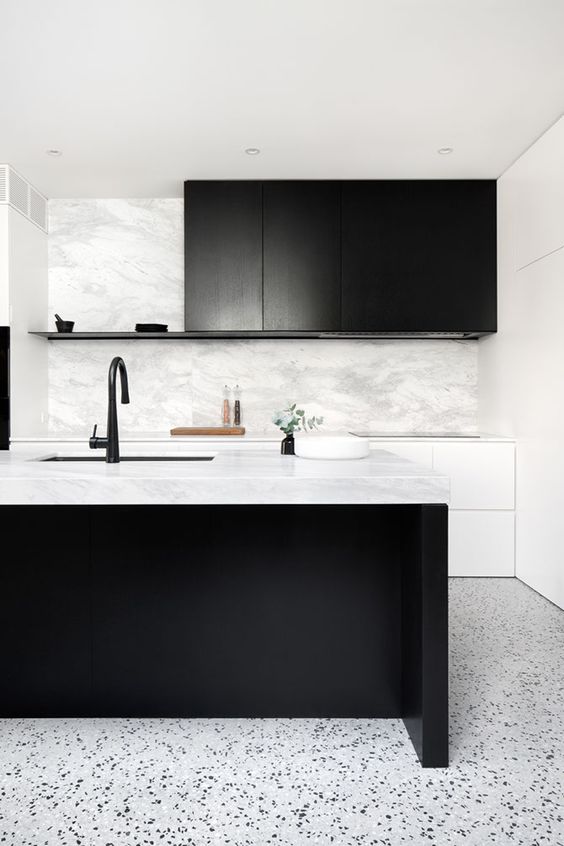 a stylish black and white kitchen with sleek white and black cabinets, a large kitchen island, black fixtures and greenery
