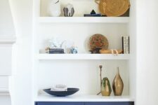 26 an arched niche with shelves that shows off stacks of books, baskets, vases and dishes plus a navy built-in cabinet for storage