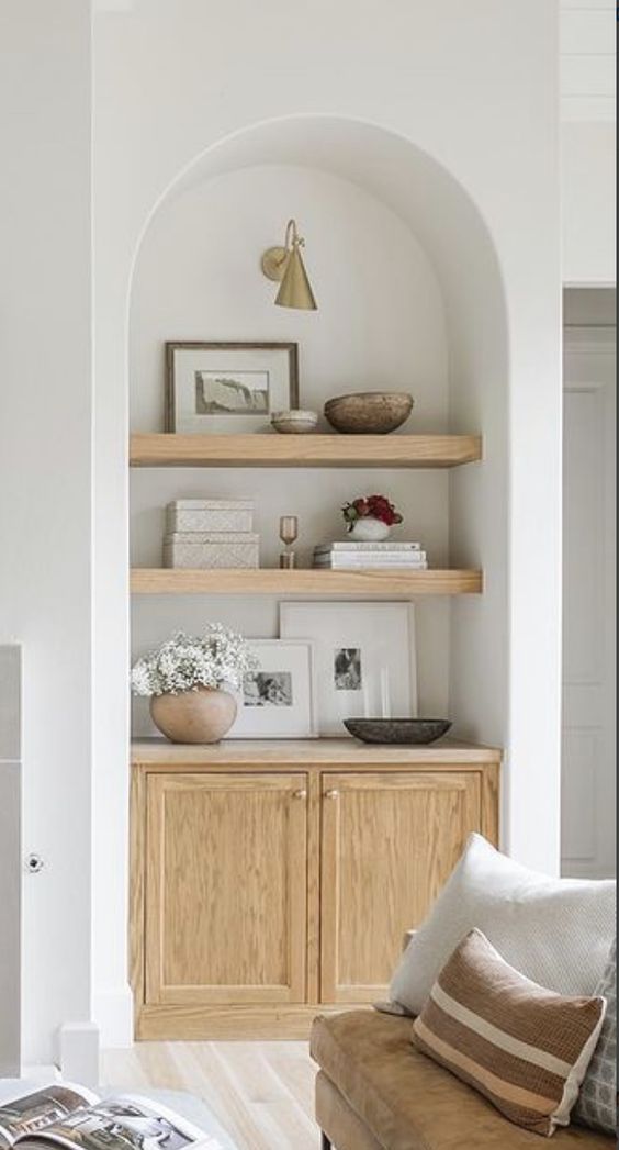 an arched niche with stained wooden shelves for storing artwork, books and decor and a built-in stained cabinet