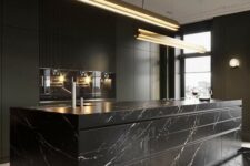 28 an exquisite black kitchen with plain cabinets and an oversized black marble kitchen island plus touches of gold